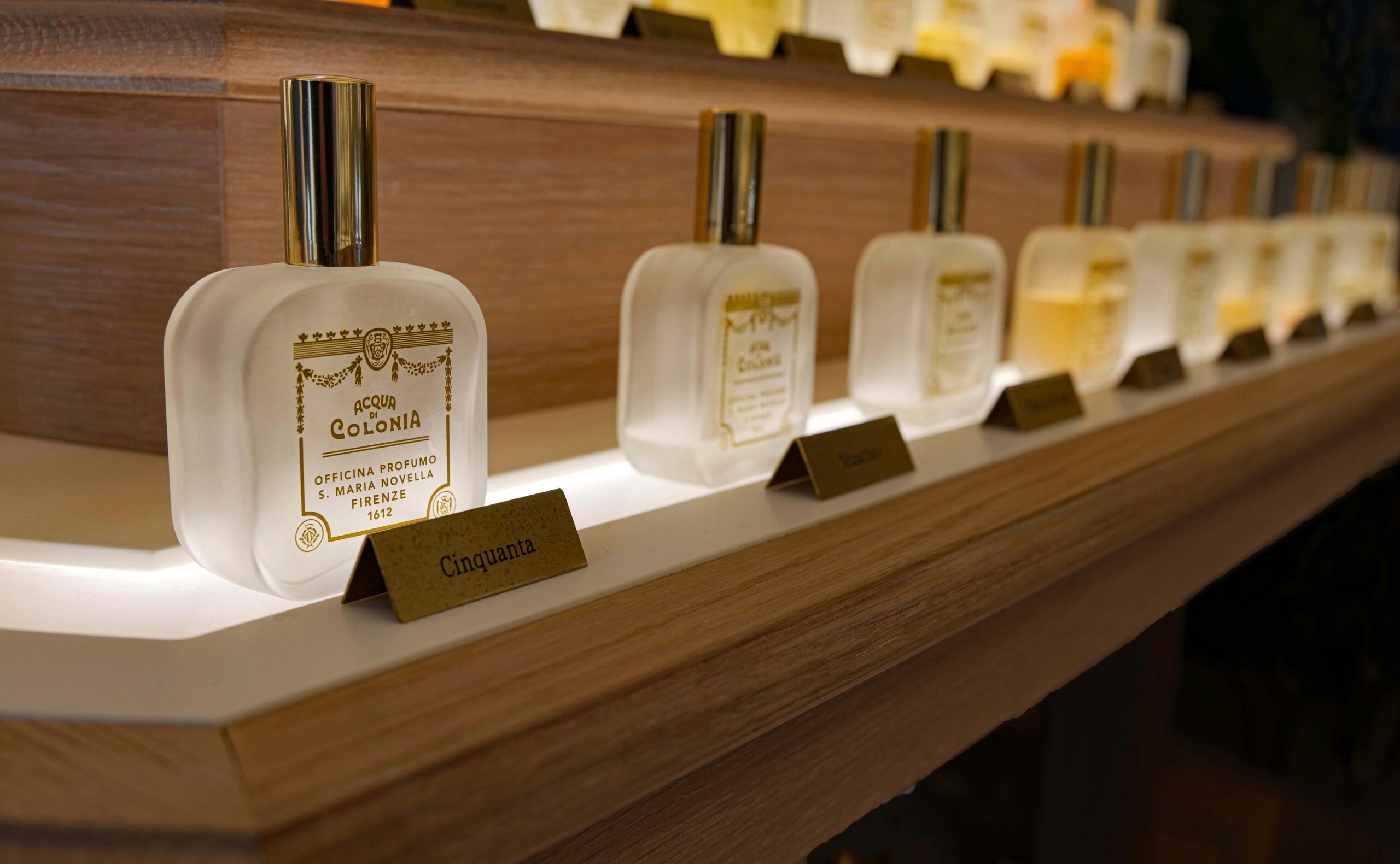 Close-up of elegant luxury perfume bottles on a wooden shelf with ambient lighting.